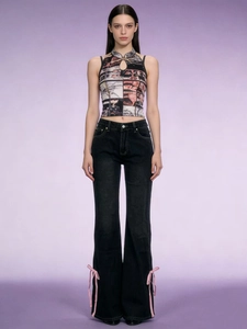 Dettaglio di fiocchi in nastro rosa su jeans neri a zampa dallo stile street fashion