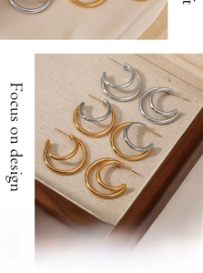 Double hoop C-shaped stainless steel earrings in gold and silver finish on display tray