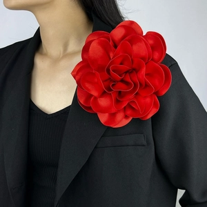 Close-up of a large 19cm red satin fabric flower brooch pinned on a black suit blazer