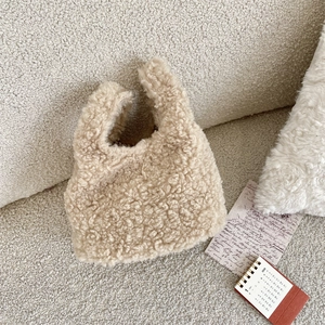 Detail of soft beige teddy fleece handbag with plush texture in a cozy winter setting