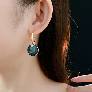 Close-up of vintage gold hoop earrings with green zircon flower drop on model ear