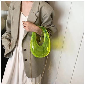 Close-up of fluorescent yellow transparent acrylic clutch bag with gold chain strap