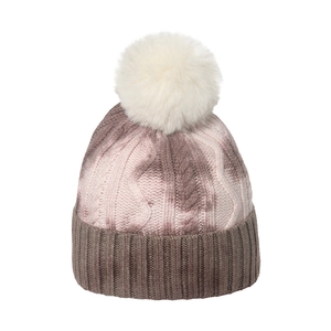 Detail of chunky cable knit texture and fluffy faux fur pompom on tie-dye beanie