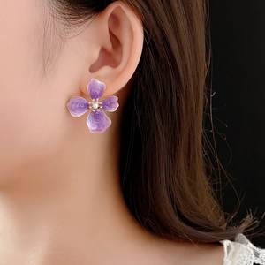 Gros plan détaillé d'une boucle d'oreille fleur mauve avec perle portée par un mannequin