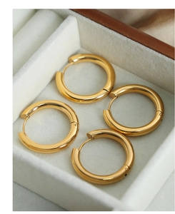 Close-up of golden geometric round hoop earrings displayed in white velvet jewelry box