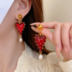 Vintage red heart earrings with pearl drops and gold accents on a model