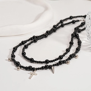 Macro shot of gothic black beads with silver cross and spike charms on a layered necklace