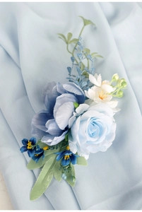 Detail of light blue silk rose and peony wedding corsage on soft chiffon background