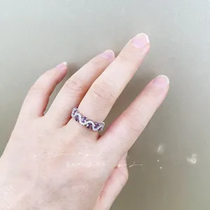 Detailed view of an elegant wavy silver ring featuring purple oval gemstones and small zircons