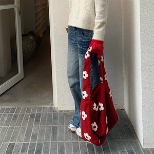 Detailed close-up of a red textured knit tote bag featuring white 3D plush flower accents