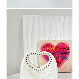 Detail of white heart-shaped acrylic evening bag with pearlescent finish and rhinestone trim