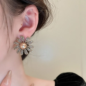 Detailed view of flower earrings with micro diamonds and a golden pearl center