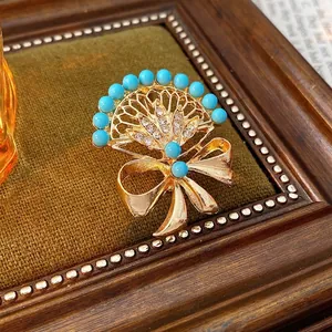 Vintage fan-shaped brooch with blue turquoise beads and sparkling rhinestone bow