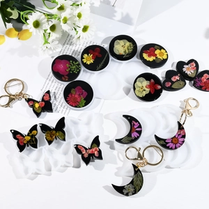 Vista de moldes de silicona de mariposa y luna con colgantes de resina y flores secas