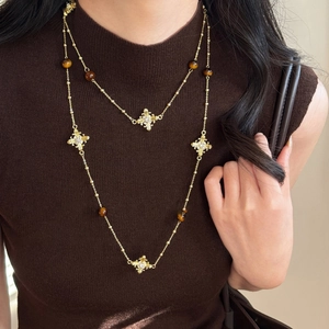 Gros plan du collier double couche en or avec perles œil de tigre et croix diamant