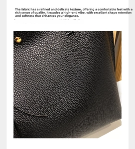 Close-up of black lychee grain texture and golden metal rivets on the tote bag
