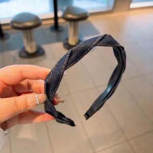 Detailed close-up of blue denim headband with twisted knot design and contrast stitching