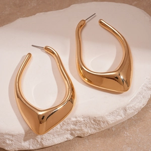 Boucles d'oreilles dorées géométriques irrégulières en métal liquide sur socle pierre