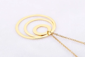 Close-up of golden geometric triple interlocking circle pendant on a delicate chain