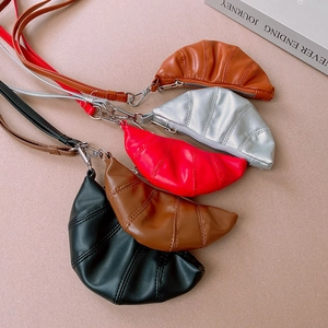 Flat lay detail showing five colors of croissant-shaped PU leather mini bags with zippers