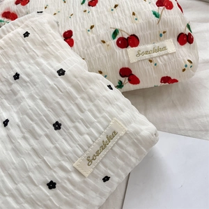 Gros plan de trousses de toilette en tissu gaufré aux motifs floraux et cerises