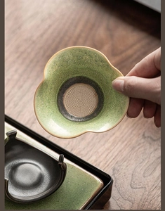 Detail view of a green ceramic clover tea strainer with fine stainless steel mesh