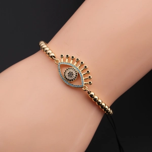 Detail of gold beaded Evil Eye bracelet with blue zircon stones on a female wrist