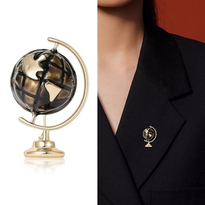 Golden alloy globe brooch with dark resin sphere on black suit lapel for stylish jewelry