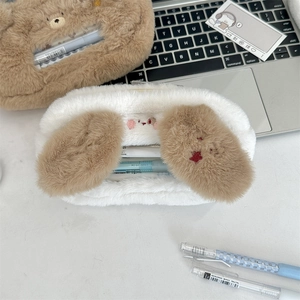 Detail of plush bear and puppy pencil cases with embroidery on a cozy student desk