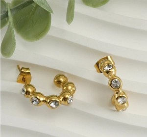 Gros plan sur des boucles d'oreilles dorées en U ornées de pierres scintillantes