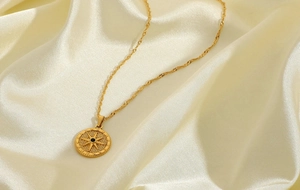 Close-up of golden octagram compass pendant with black gemstone on silk background