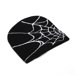 Detailed view of the black knit beanie featuring a white spider web jacquard pattern