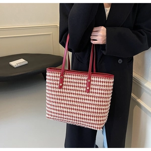 Detailed view of red houndstooth tote bag featuring woven texture and red handles