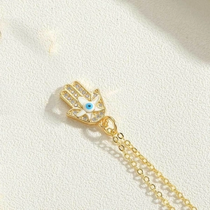 Macro shot of gold Hamsa Hand pendant with cubic zirconia and evil eye detail