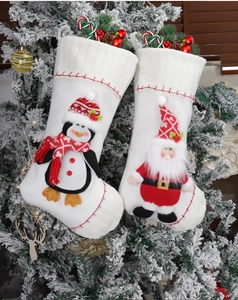 Detail of white Christmas stockings with 3D Santa and penguin hanging on snowy tree
