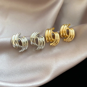 Detailed view of intertwined triple hoop earrings in polished gold and silver finishes