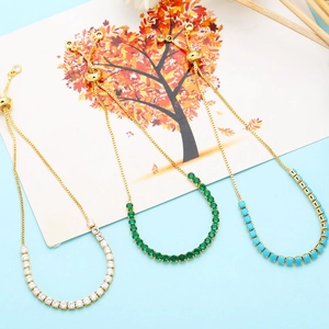 Detailed view of adjustable gold-plated bolo bracelets with zircon and emerald stones