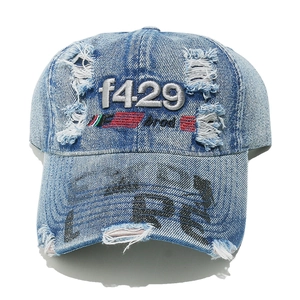 Close-up of distressed light blue denim baseball cap with embroidery and frayed holes