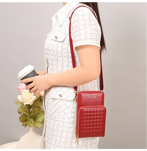 Detail of red quilted crossbody phone bag with Smile Candy logo for urban commute