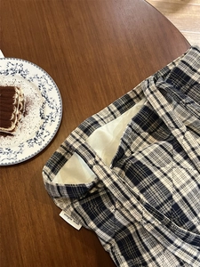 Close-up of quilted plaid cotton tote bag with side label on dark wood table setting