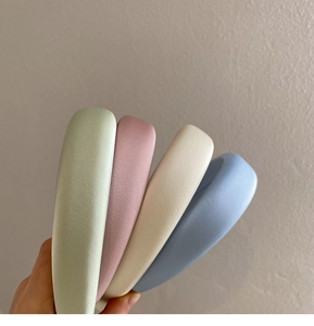 Close-up of candy-colored thick padded sponge headbands in green, pink, beige, and blue