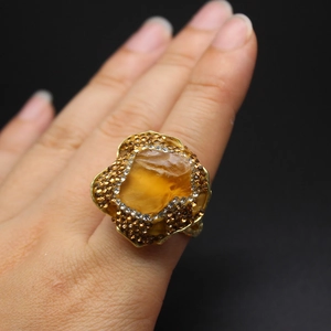 Detail of luxury gold ring featuring raw yellow amethyst stone and sparkling rhinestones
