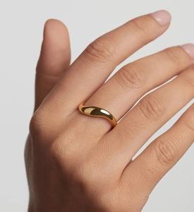 Macro shot of a golden wavy minimalist ring showing polished metallic reflections on a hand