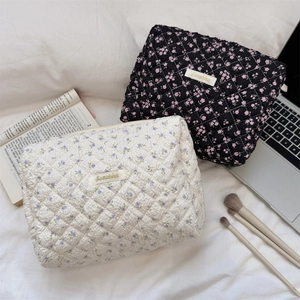 Close-up of quilted floral cosmetic bags in black and white patterns on soft bedding