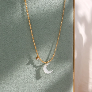 Gold asymmetrical bead chain necklace with a crescent moon shell pendant and crystal accent