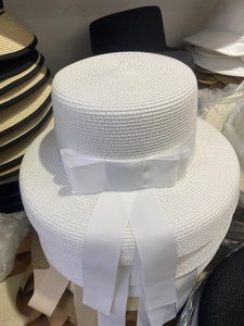 Close-up of white boater straw hat featuring an elegant wide ribbon bow detail