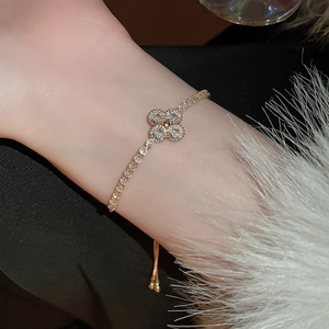 Makro-Detail des vergoldeten Kleeblatt-Armbands mit Zirkonia-Steinen an der Hand