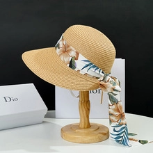Detail of wide brim straw sun hat with floral silk scarf on a wooden display stand