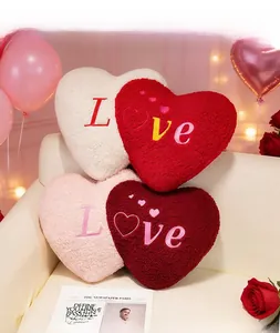 Detail of plush heart-shaped pillows with 'Love' embroidery and soft teddy fleece texture