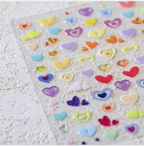Macro detail of colorful 3D heart nail art stickers on a textured background